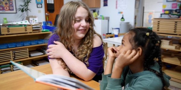middle school student reading with kindergartener