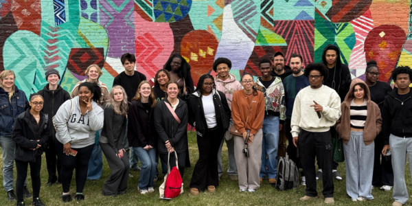 students posing in front of a mural