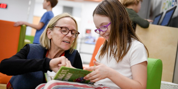 STEP volunteer reading a book with an elementary student
