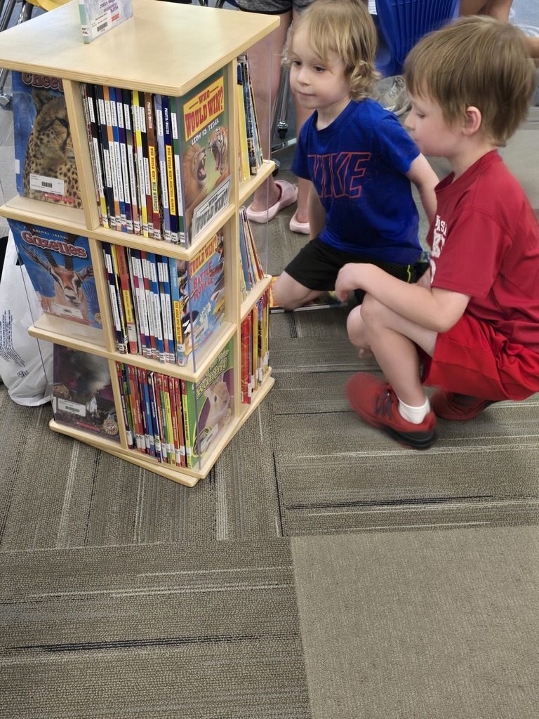 boys looking a spinning book shelf with books
