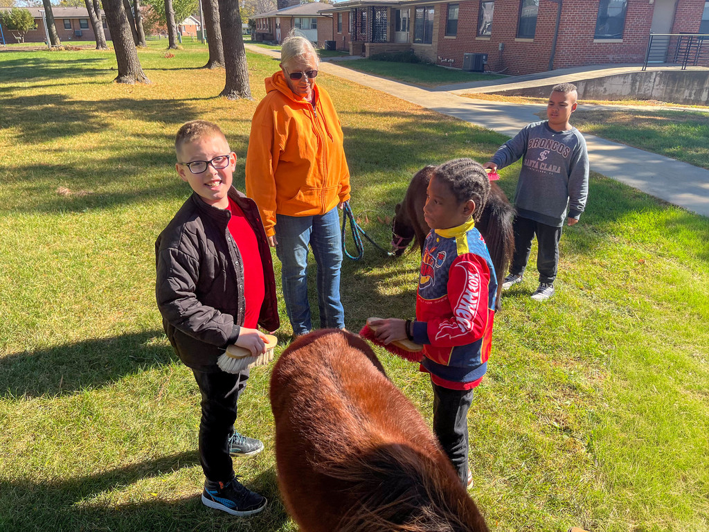 3 children posing for a picture with two mini horses