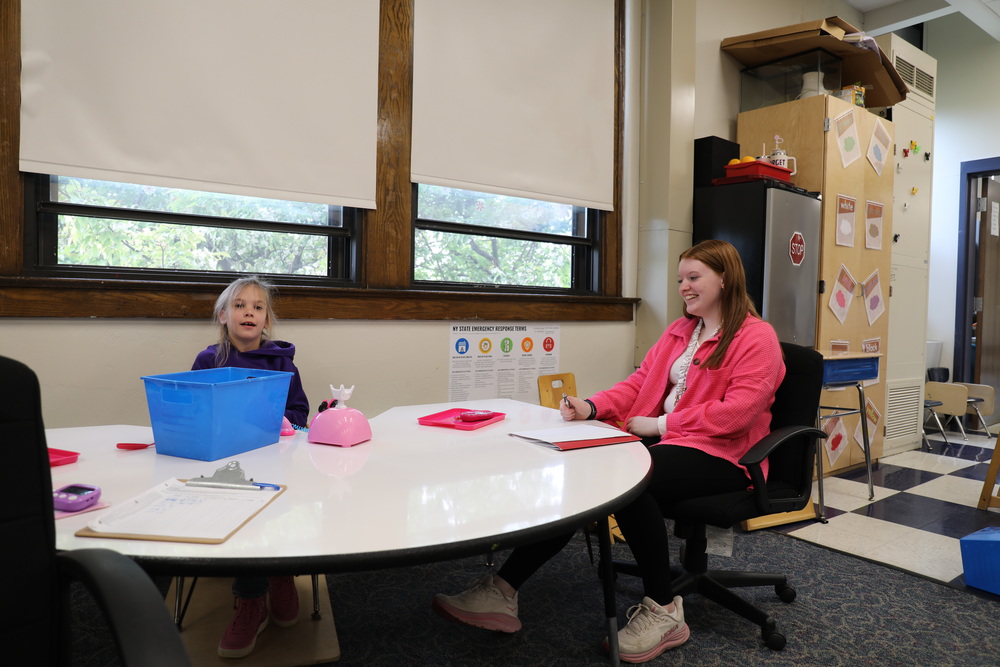 A FLTCC student sits at a table with a NEC student