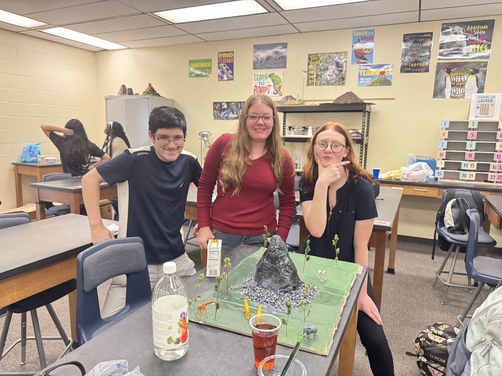 Three students with their volcano model at a table.