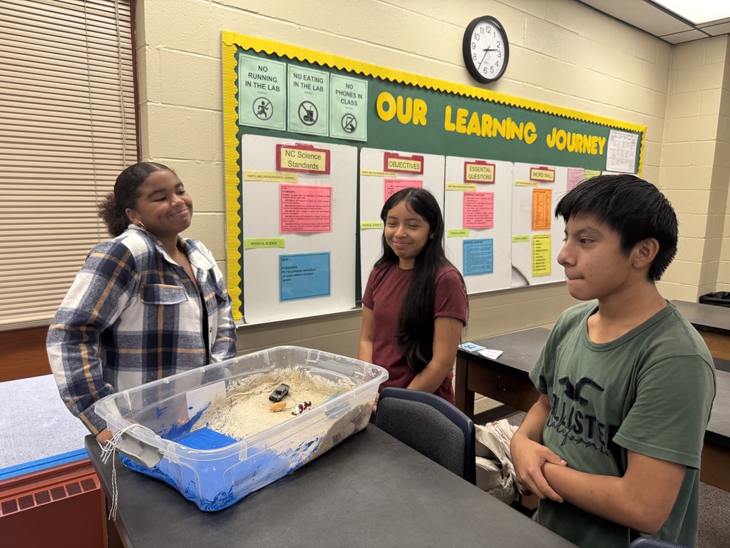 Students in a classroom with the model of the beach that they created.