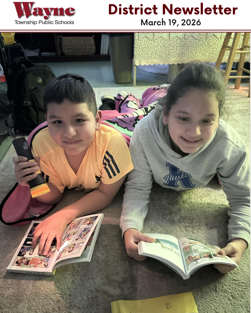 Two children lie on a carpeted floor, each holding a book. A boy holds a flashlight. Behind them, various items are on the floor, including a backpack and a storage box.