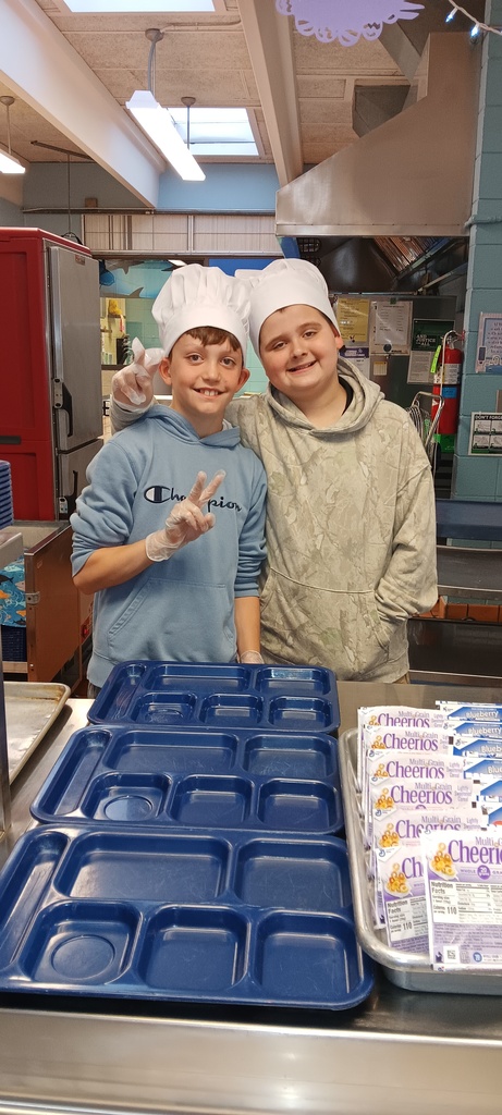 Two student volunteers wearing hats in the kitchen in the cafeteria