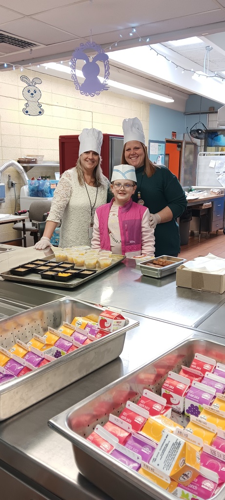 Two adult volunteer and one child in a school kitchen