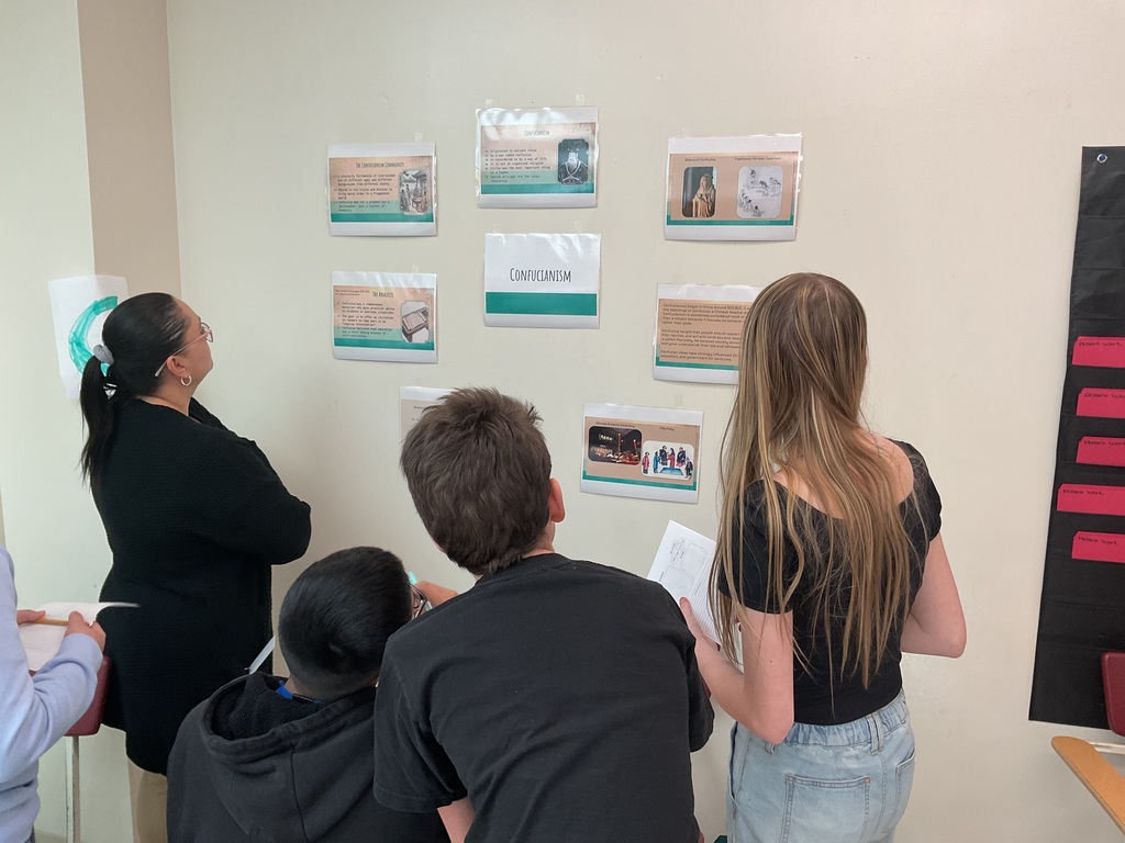 Students looking at Confucianism station and writing facts in their passports