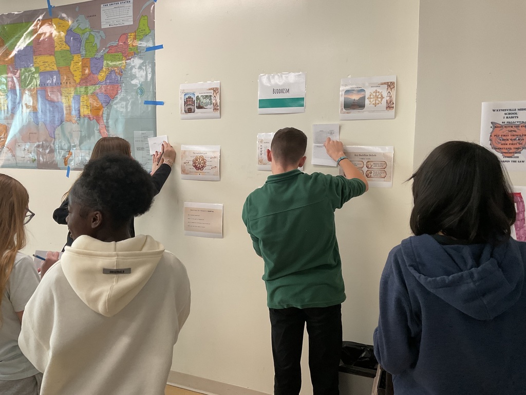 Students looking at Buddhism station and writing facts in their passports