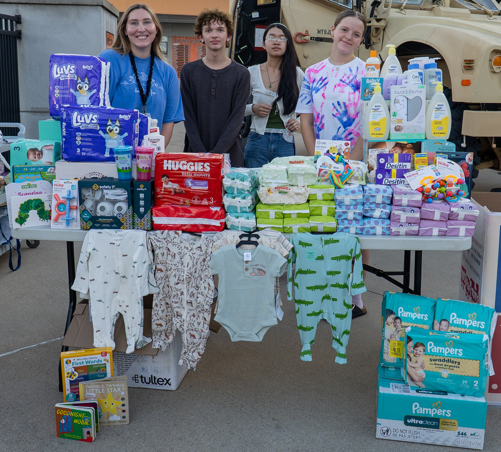 3 whs students and a whs teach posing for a photo near baby items