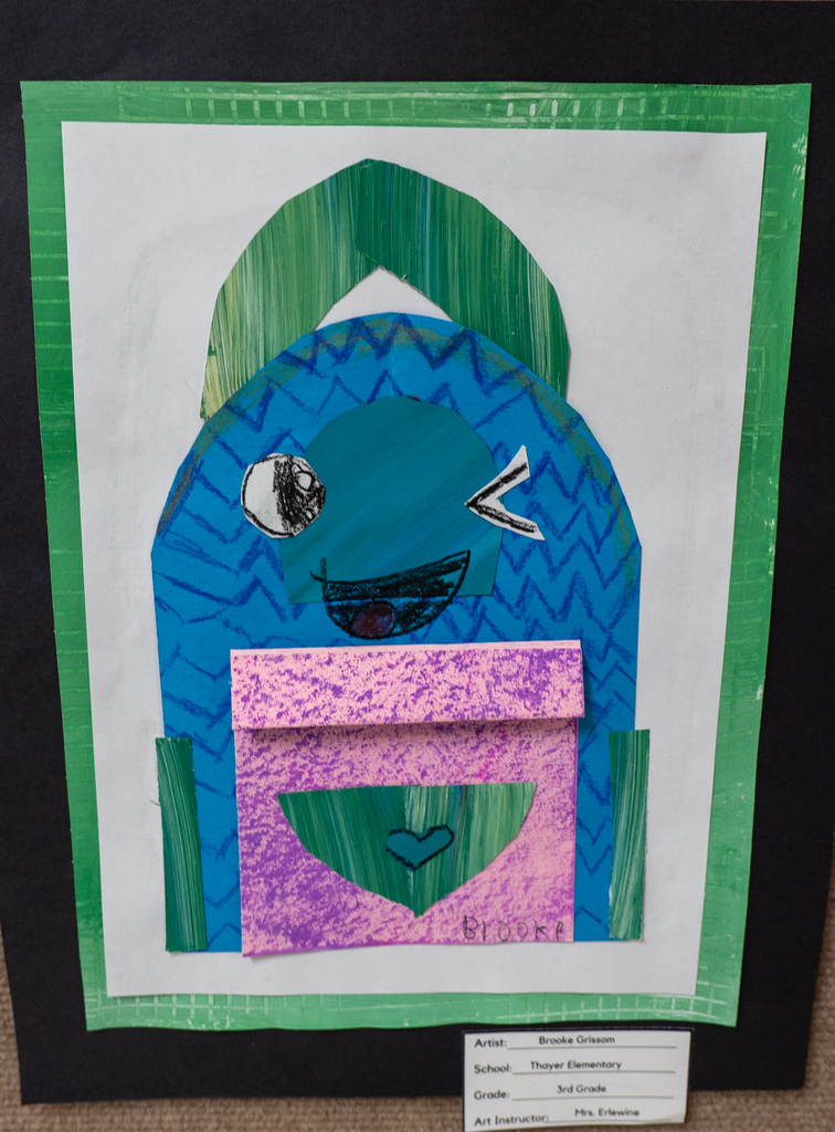 artwork on display featuring a blue character with a pink box in front.
