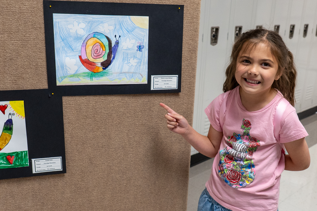 Student pointing to her artwork of a snail.