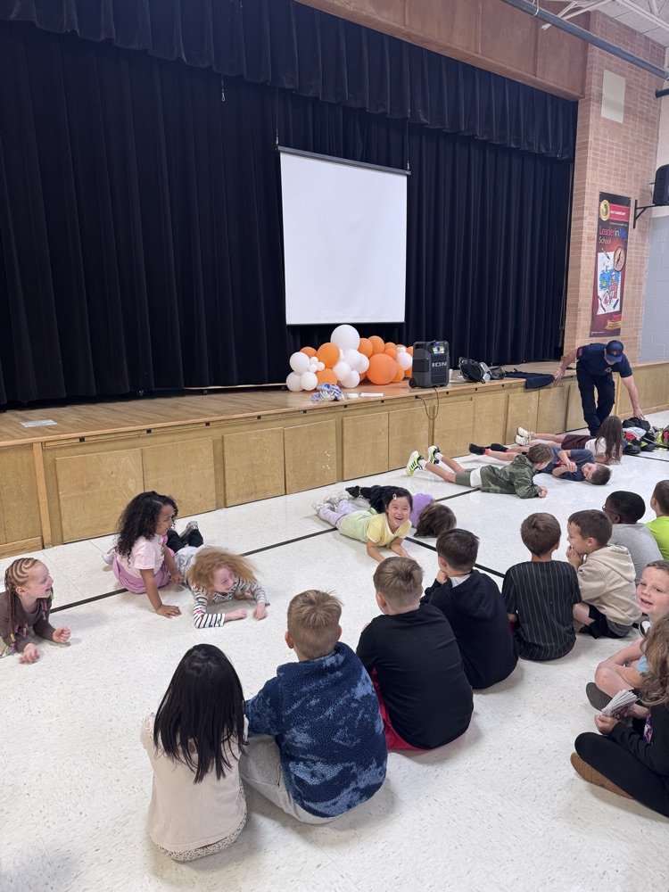 a group of students practicing the Stop, Drop, and Roll. Another groups of students sitting and watching
