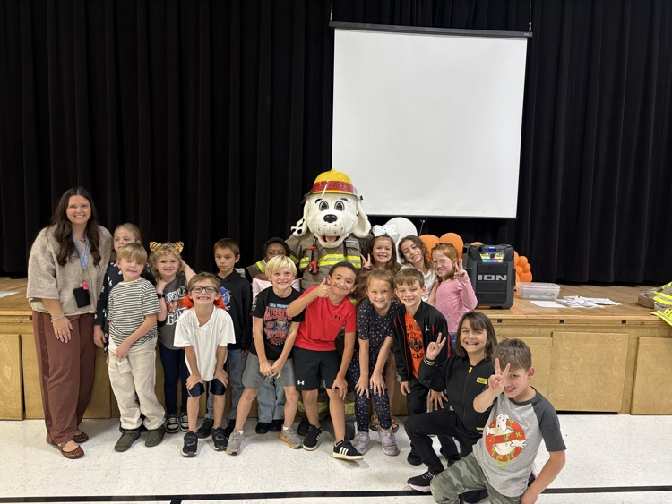 15 students and a teacher standing with the fire dog (mascot) posing for a picture