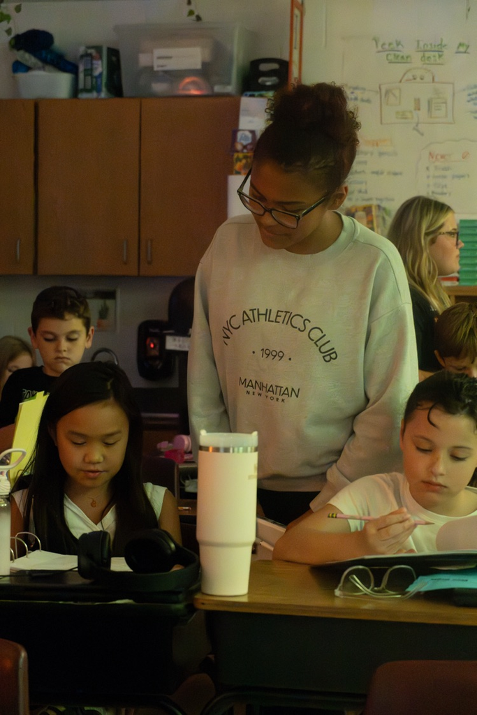 A female student helping a kindergartner with her work.