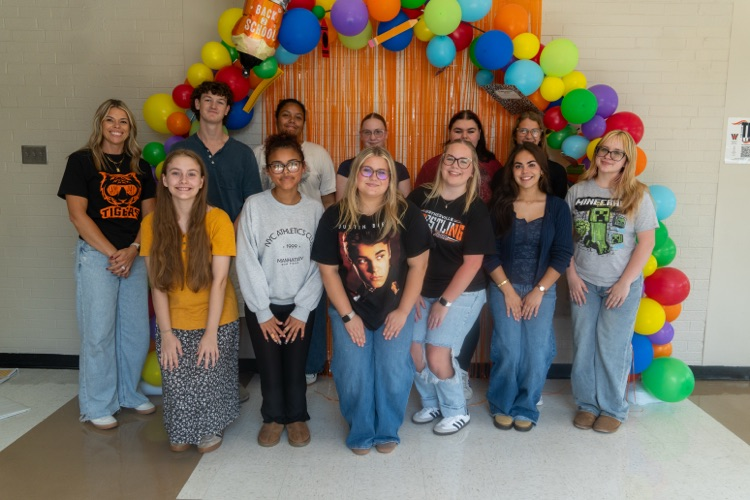 teaching pathways students gathered together under a ballon arch.