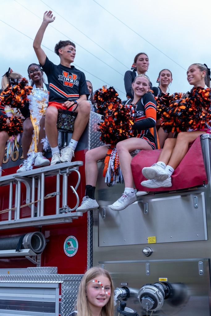 Cheerleaders riding on a firetruck in the Homecoming Parade