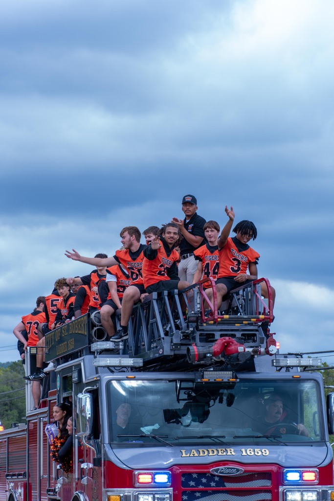 Football players riding on a firetruck in Homecoming Parade