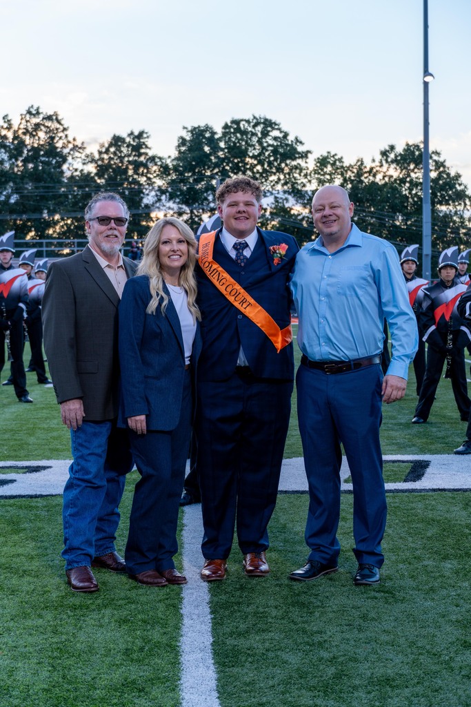 A male High School with his mom, dad, and step dad.
