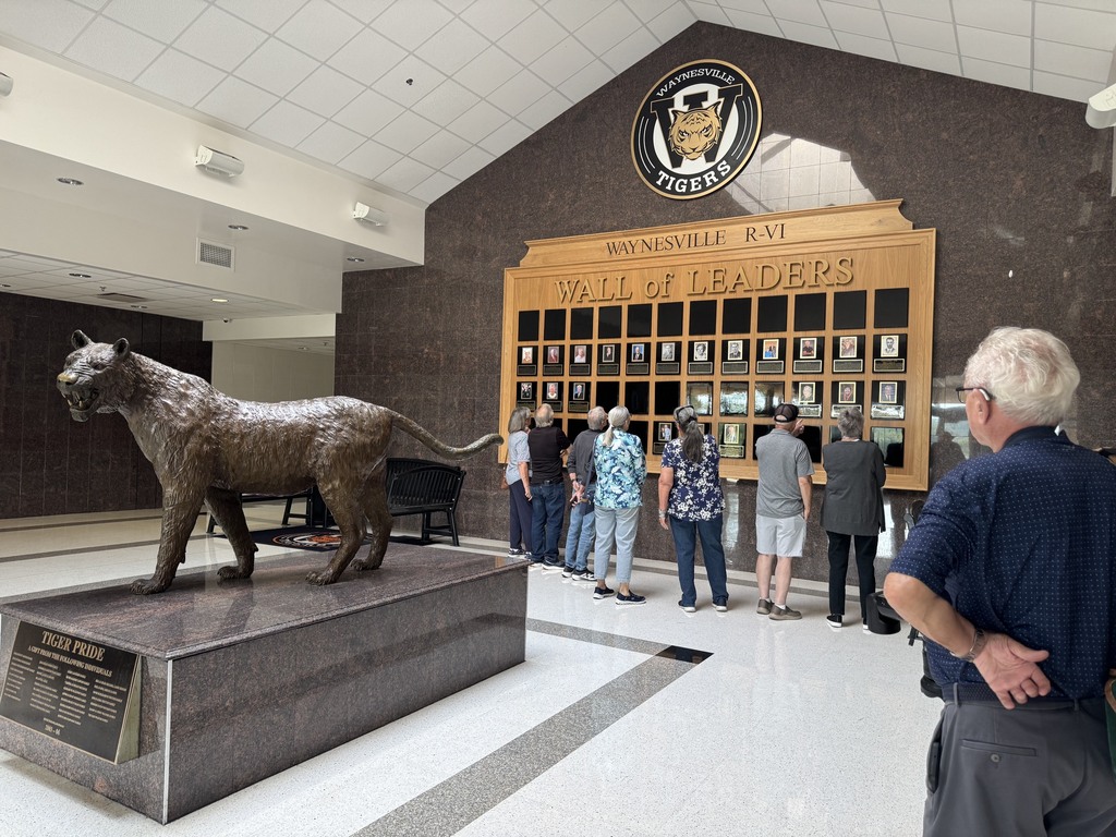 Members of the Class of 1966 and their spouses looking at the Wall of Leaders in Waynesville High School.