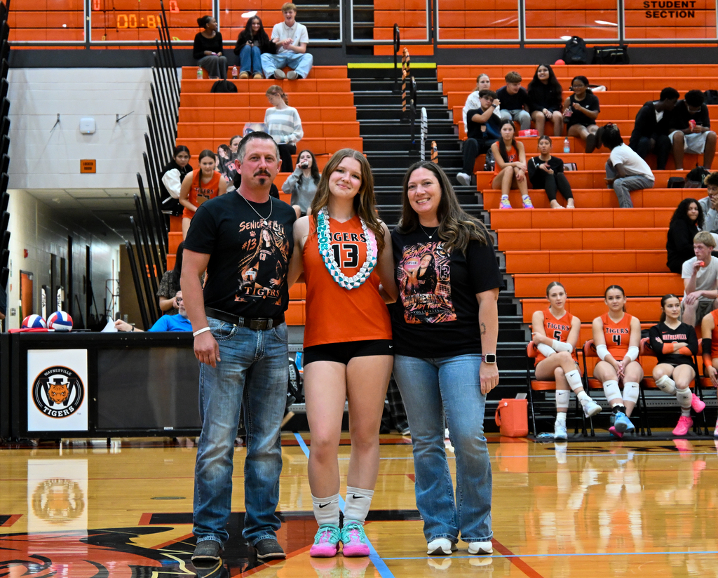 A female student being walked out by her parents on her senior night for Volleyball.
