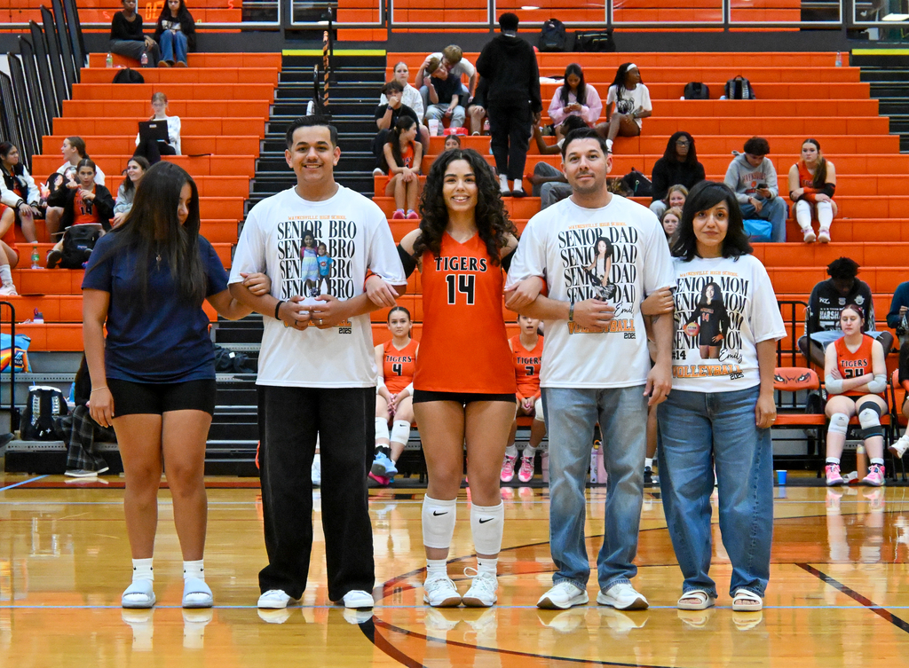 A female student being walked out by her parents on her senior night for Volleyball.