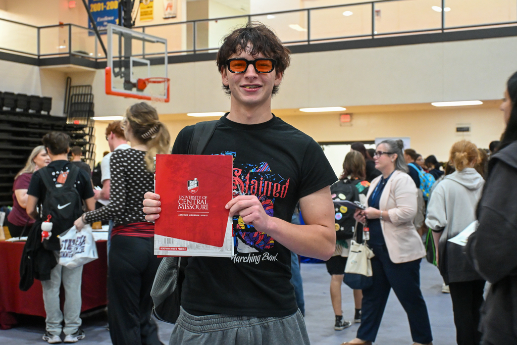 A student posting with a school flyer