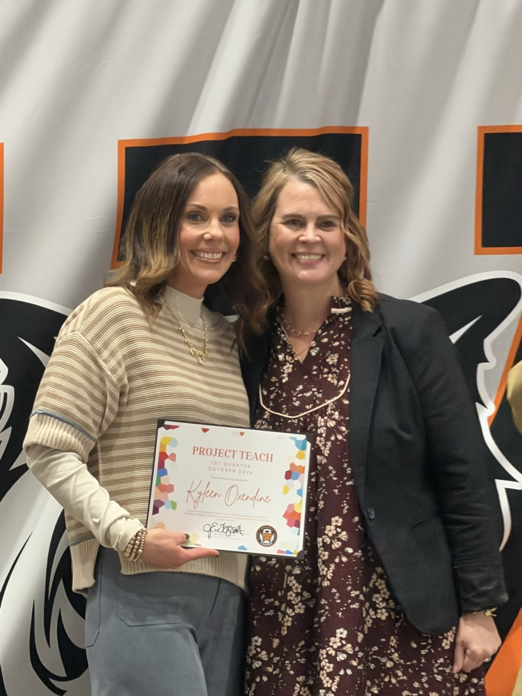 2 female adults posing for picture with an award