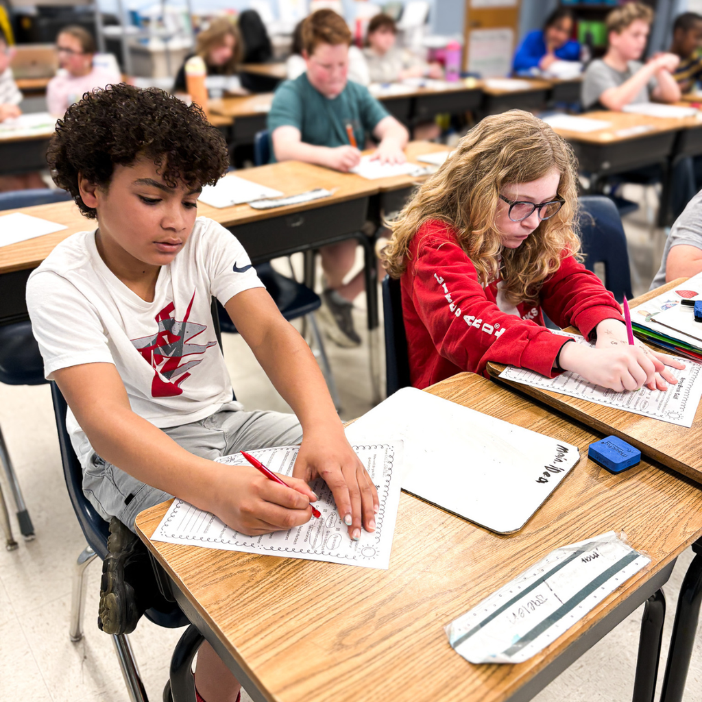 Students work independently at their desks, completing worksheets and writing responses related to identifying the main idea.