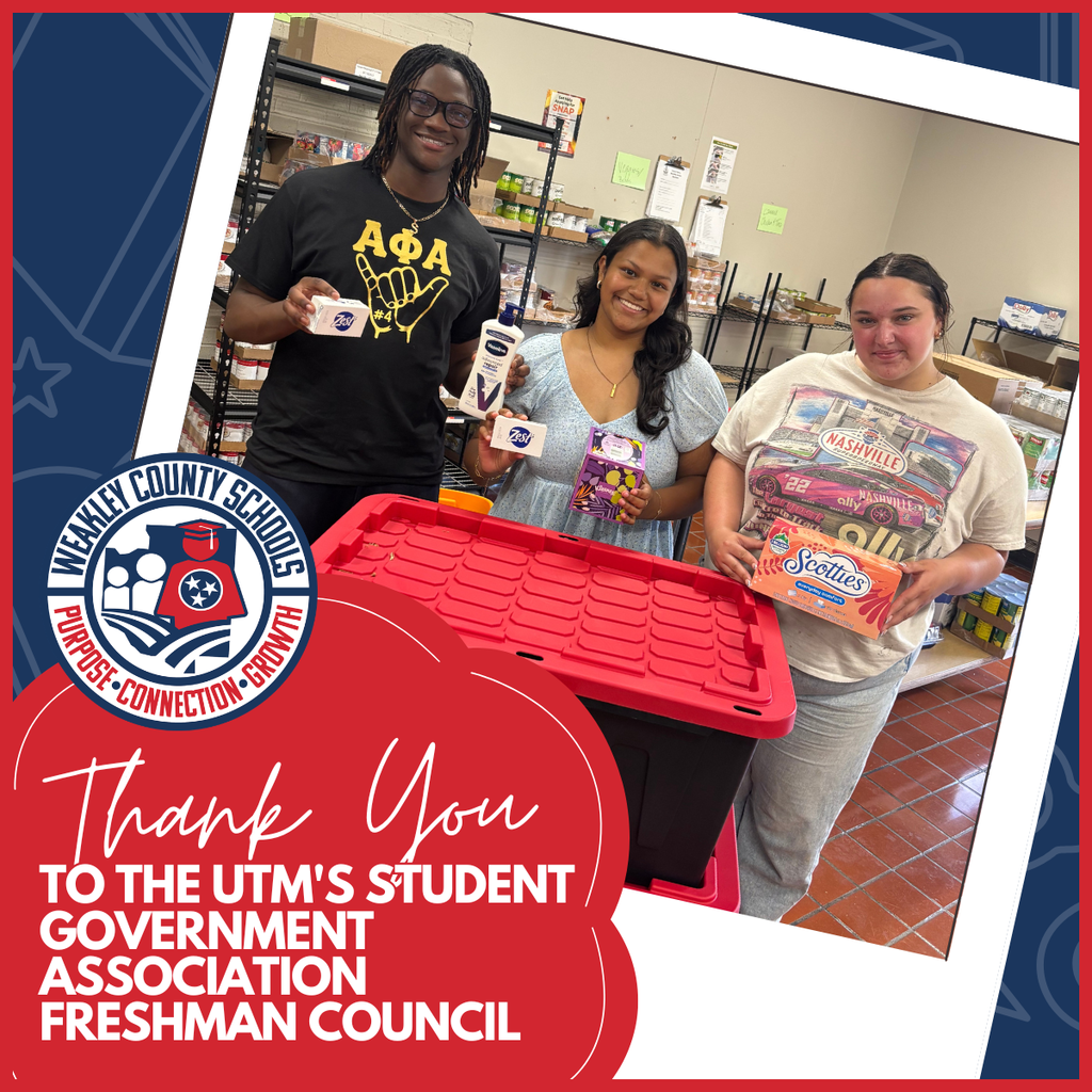 Three people holding items stand in front of a red storage box. They are in a store.