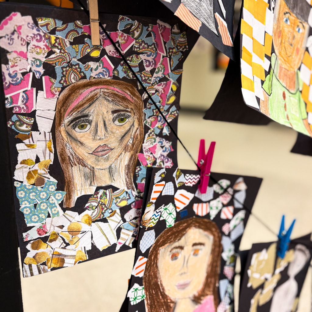 Portraits of women with varied expressions hang from a line with colorful, abstract backgrounds and decorations.
