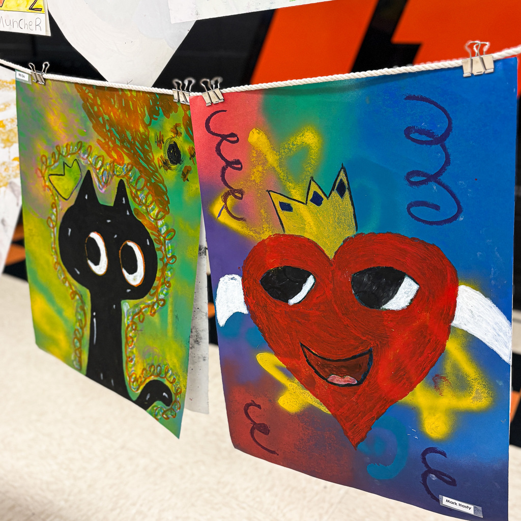 Three colorful artworks hang on a wall, one featuring a black cat, and the other a heart with a crown.
