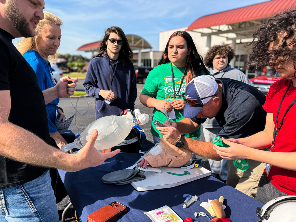 A group of people around a table with a dummy, examining a prosthetic leg.