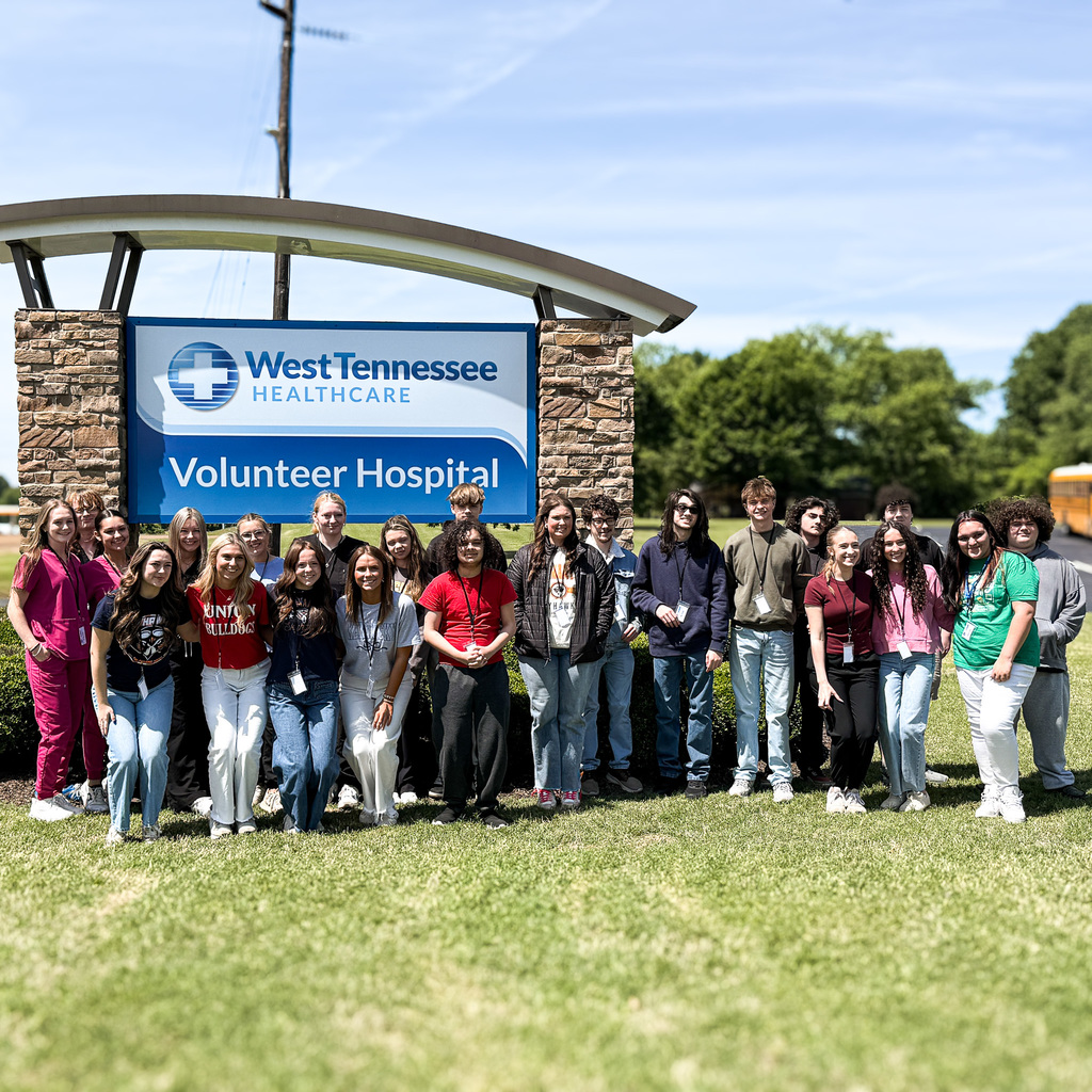 A group of volunteers stands in front of a sign reading "West Tennessee Volunteer Hospital."