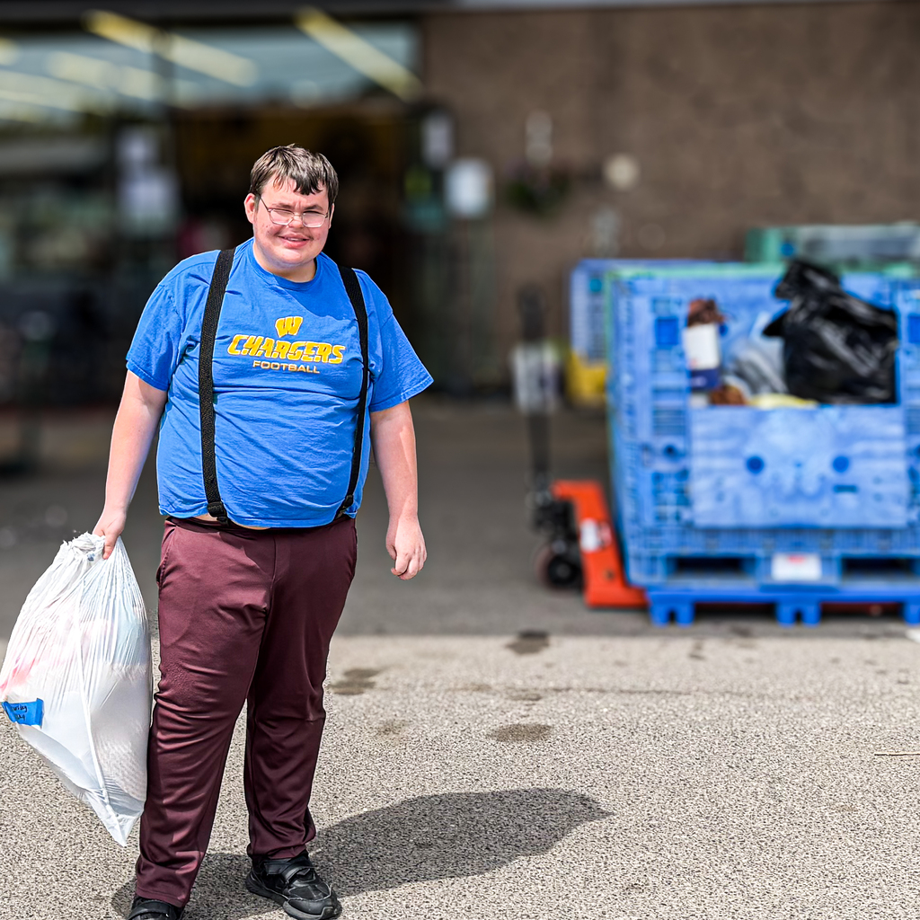 A man in a blue shirt holds a plastic bag.