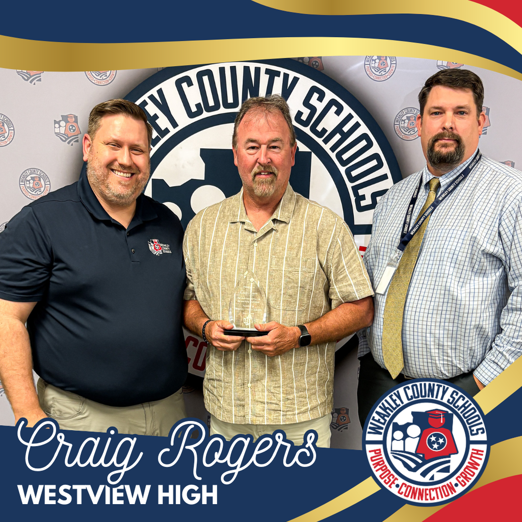 Three men pose for a picture, with the middle one holding an award. Background reads "KNOX COUNTY SCHOOLS".