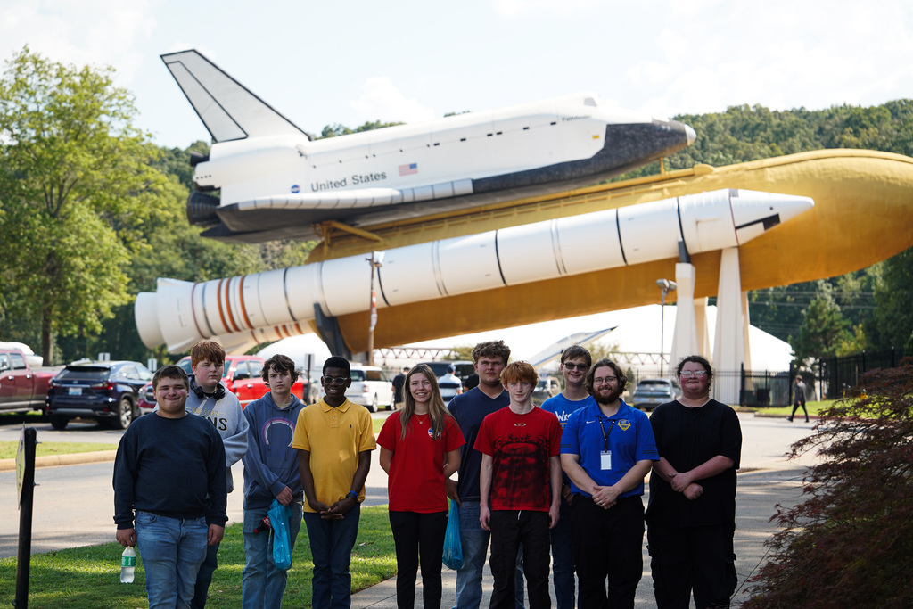 Dresden and Westview students and staff pose beneath a space shuttle and rocket display during their visit to NASA’s Marshall Space Flight Center.