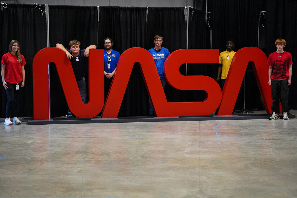 estview High School students and a staff member pose around a large red NASA logo during their visit to Marshall Space Flight Center.