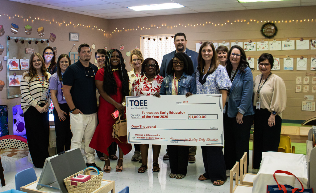 chaela Frederick stands with family members, colleagues, and school and district leaders in her Sharon School classroom while holding an oversized $1,000 Tennessee Early Educator of the Year award check.
