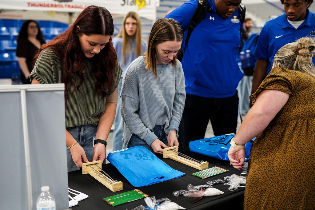 A group of people examine a table of career fair materials.