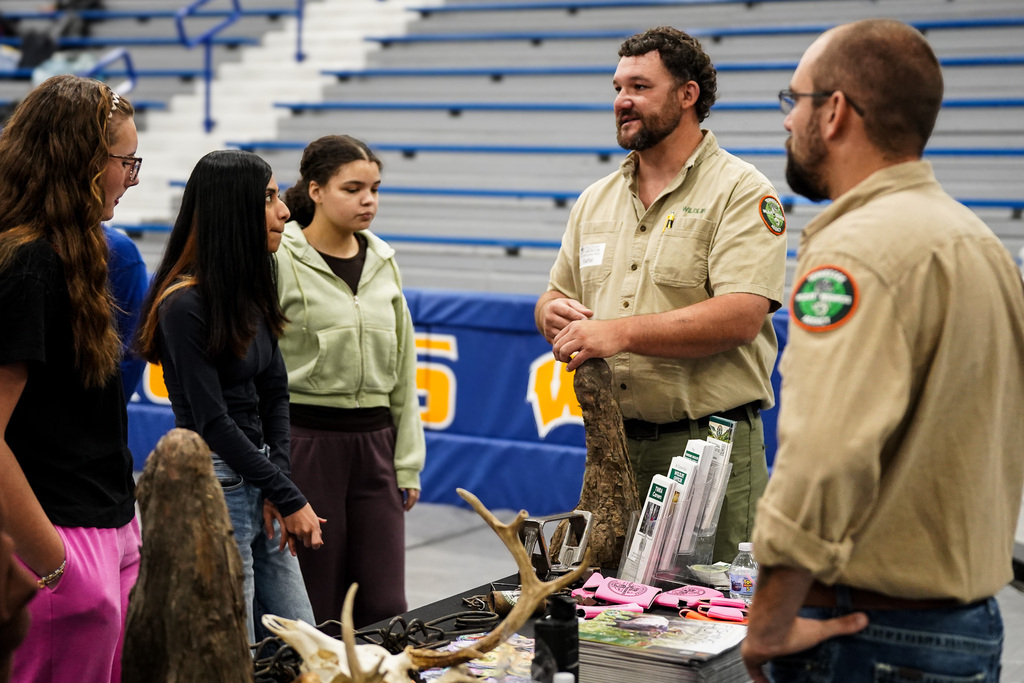 A group of students at a career fair learn about wildlife resource agency careers