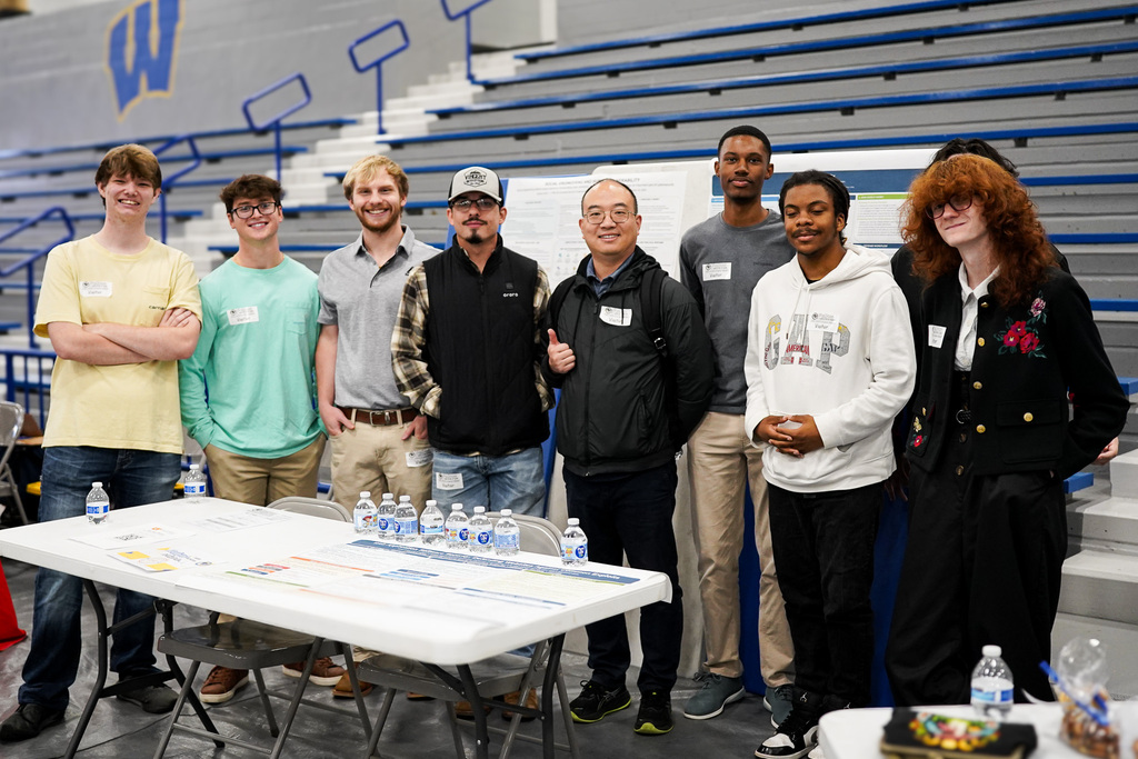A group of engineering students speak to career fair attendants.