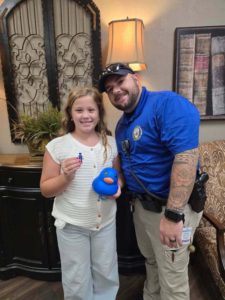 SRO and student standing together in office after student found the little SRO in the building on scavenger hunt.