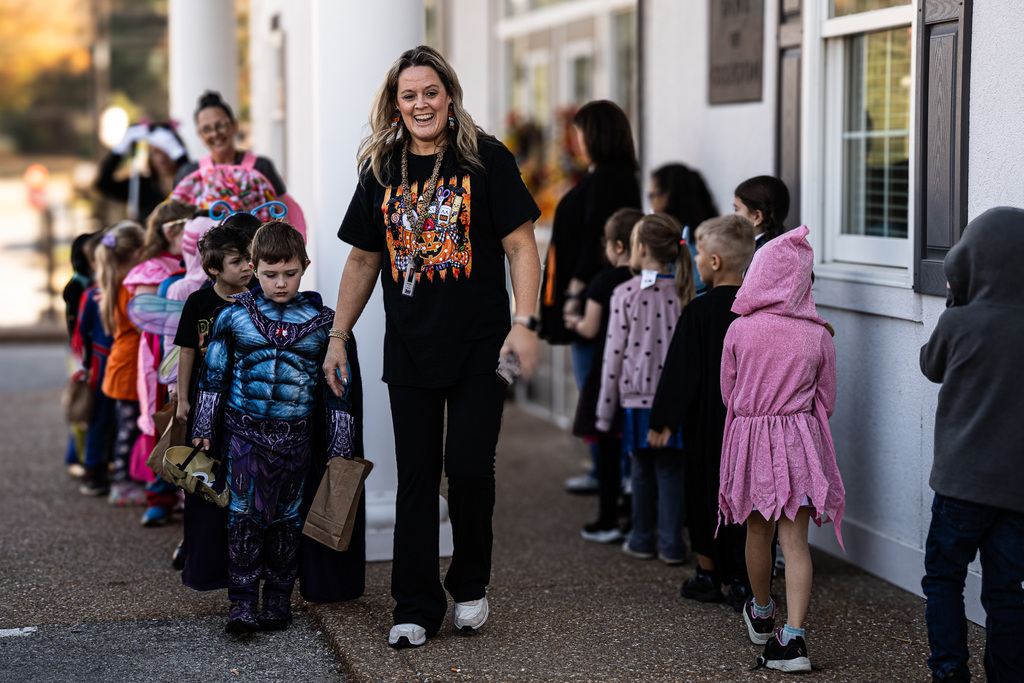 a teacher leads a group of trick or treaters