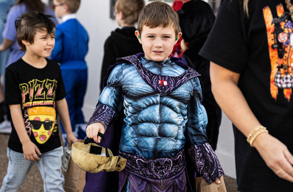 a child is trick or treating dressed as a superhero