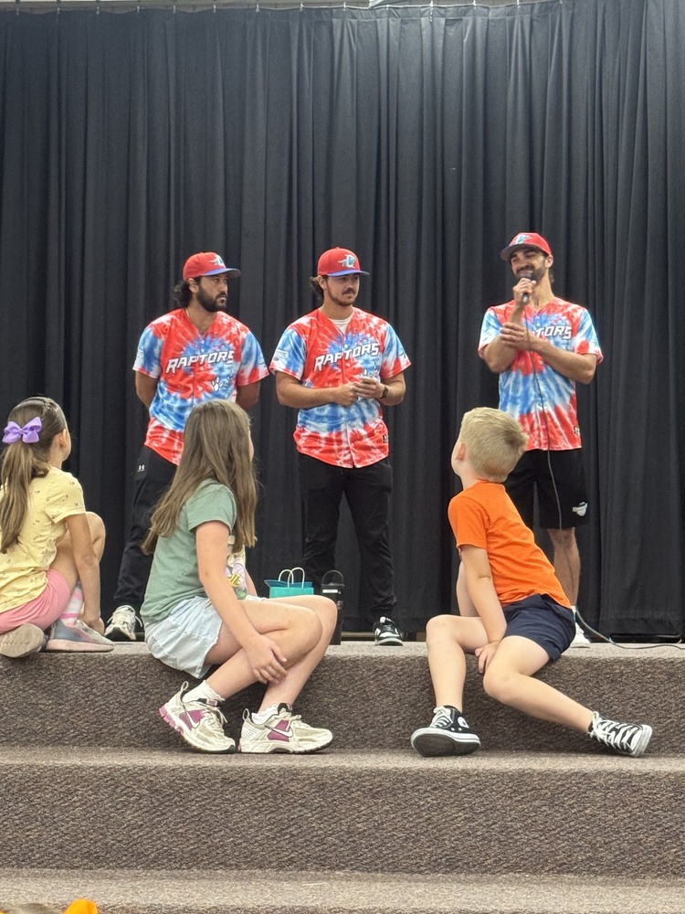 Ogden Raptors players standing on the stage speaking into microphone, while select students chosen to come up and ask questions sit and listen