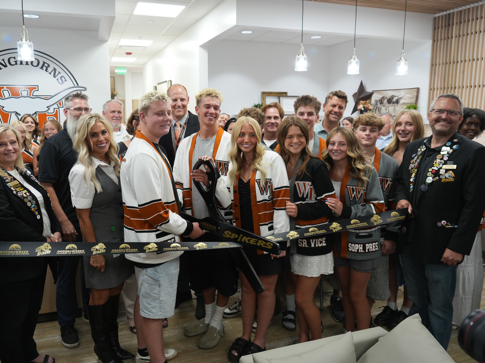A group of district and community leaders with west field high students about to cut a ribbon in the new West Field High Teen Center.