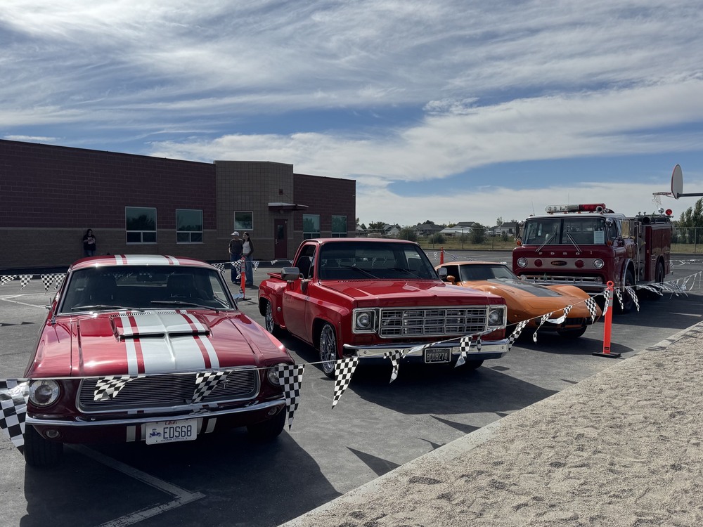 picture of old cars in a line in front of plain city elementary