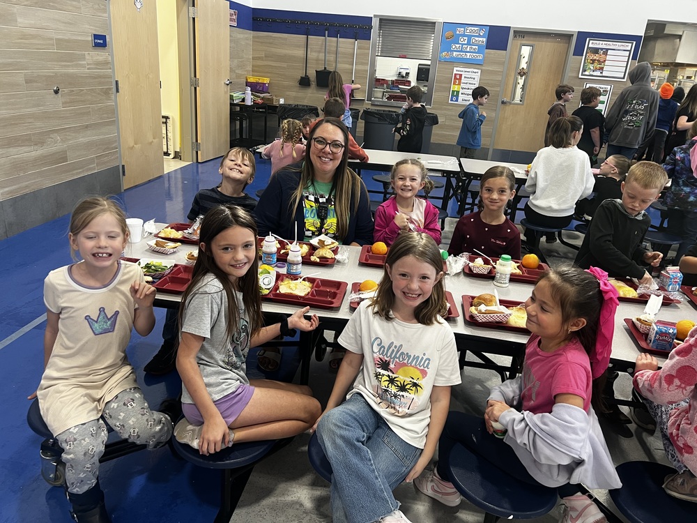 image of students with a teacher eating lunch in the lunchroom