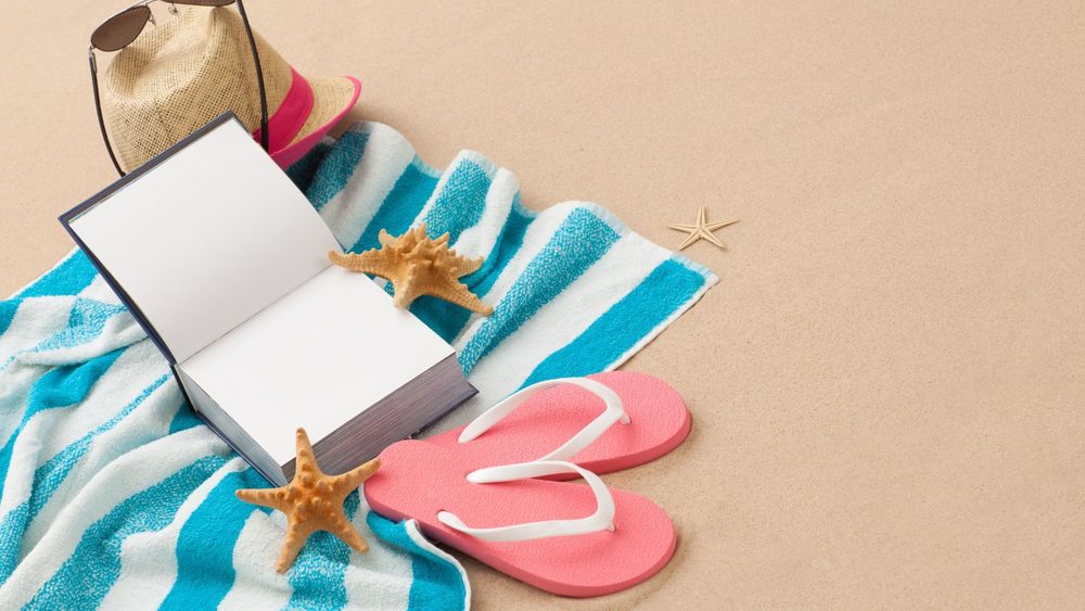 a book open on a towel with shoes and star fish